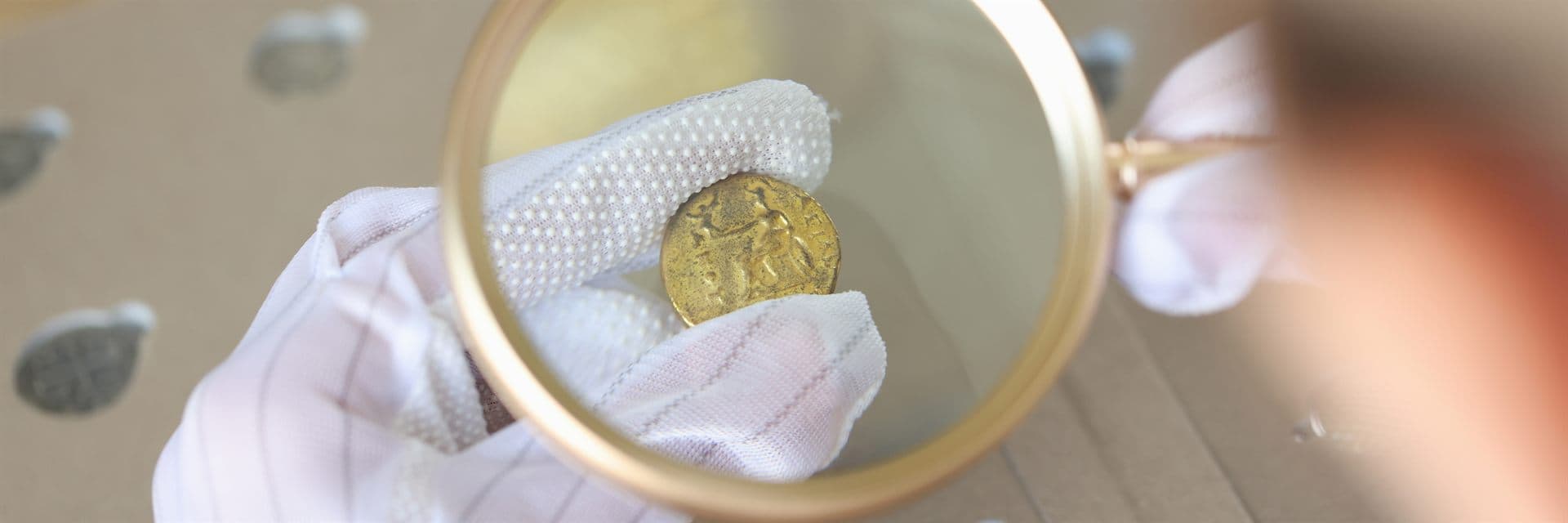 Examen con lupa de una moneda antigua durante su tasación en A Coruña